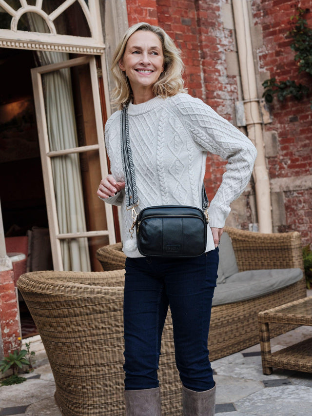 Woman carrying the Pom Pom London Original Plus leather crossbody bag in Black